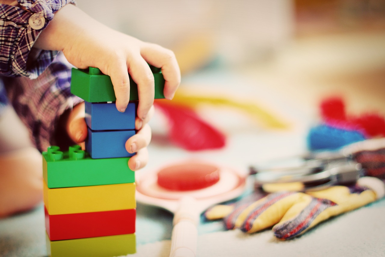 Manos de niño haciendo una torre con piezas de colores