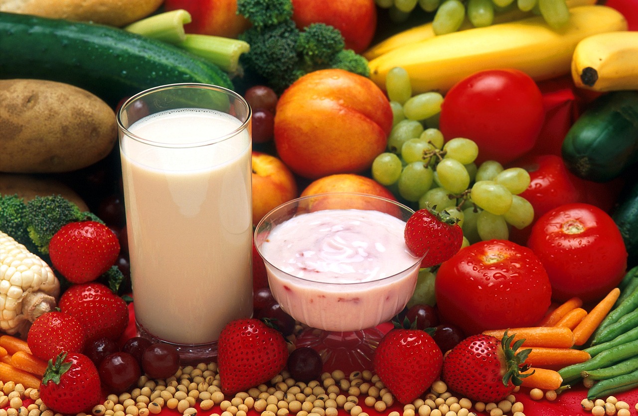 Un vaso de leche, un ygur en vaso y fruta en una mesa