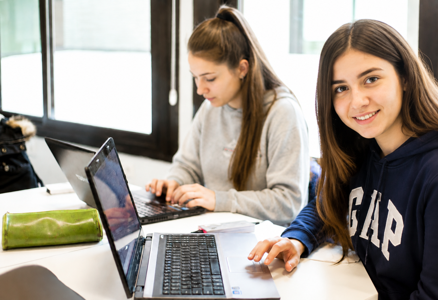 Dos estudiantes trabajan con ordenadores portátiles en un aula, imagen representativa del Grado Superior de Administración y Finanzas a Distancia de la UFV.
