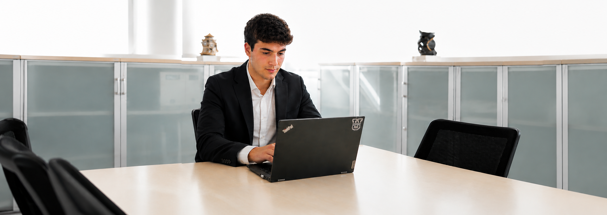 Estudiante trabajando con un ordenador portátil en un entorno profesional, imagen representativa del Grado Superior de Administración y Finanzas a Distancia de la UFV.